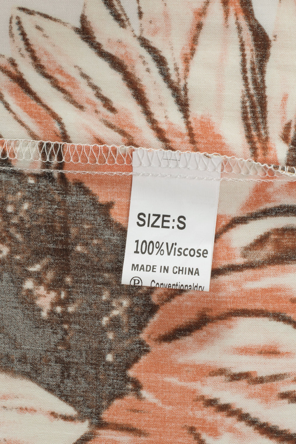 Floral ruffled blouse fabric label showing size S and 100% viscose fabric care details.