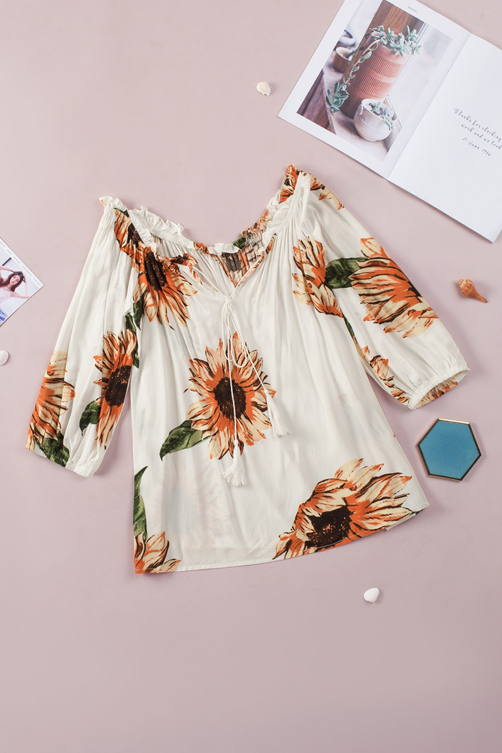 Off shoulder floral blouse with sunflowers, ruffled sleeves, and tassel ties, perfect for a playful and feminine look.