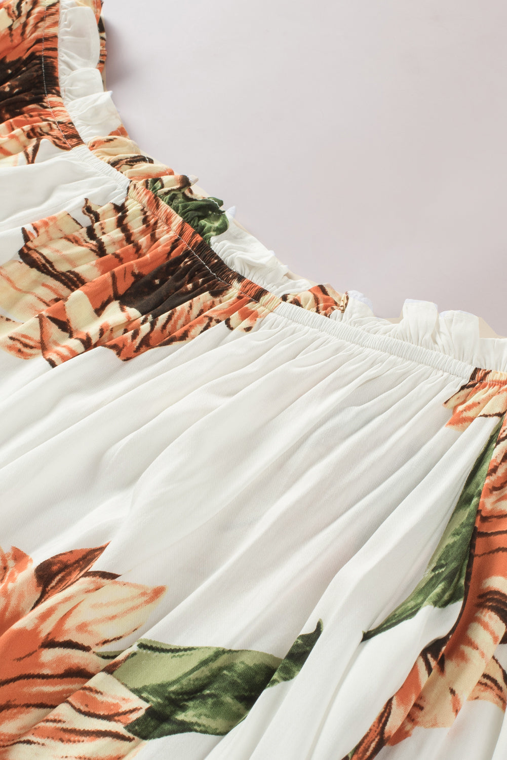 Close-up of floral ruffled tassel tie off shoulder blouse featuring vibrant sunflower print and flouncy detailing.