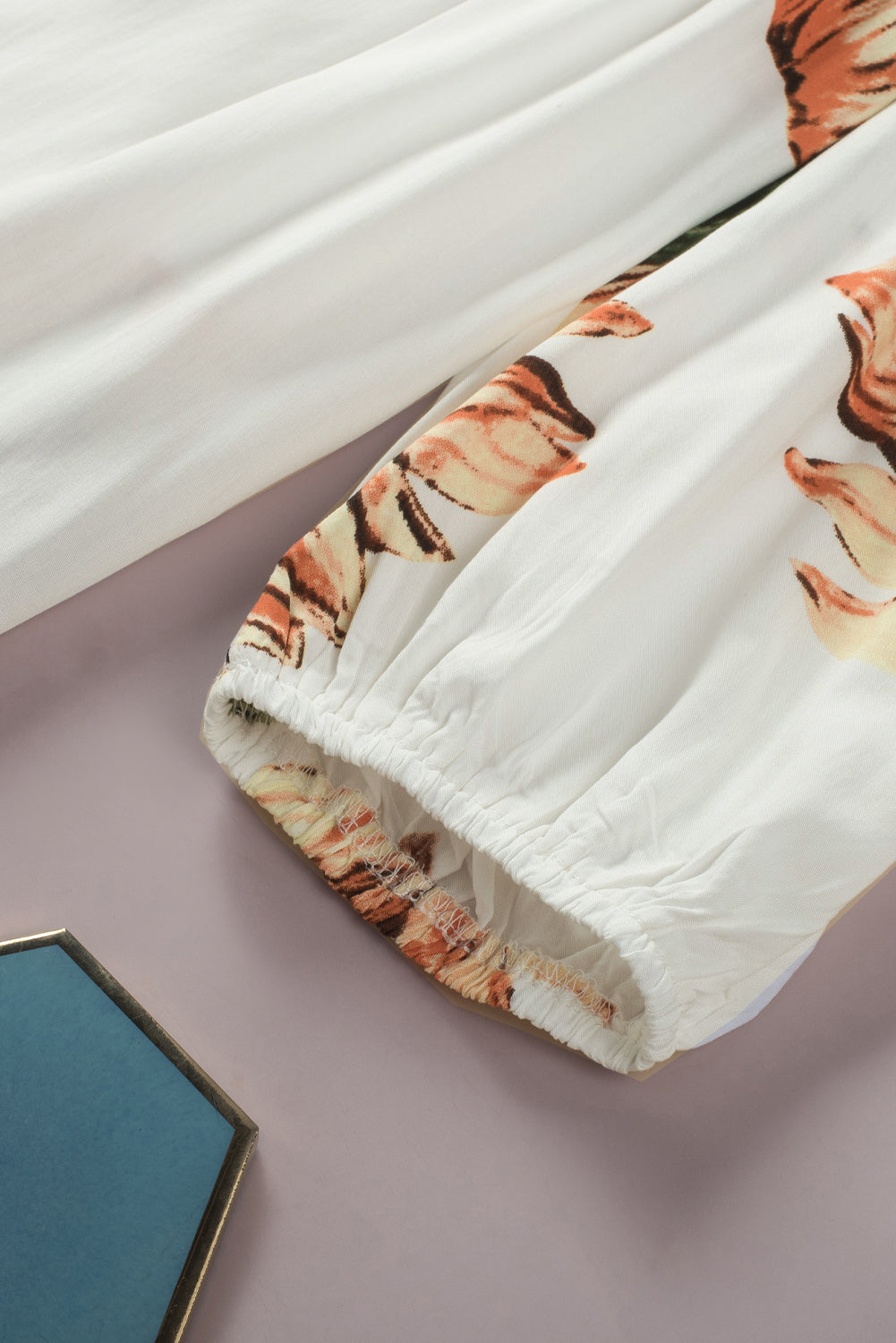 Close-up of floral ruffled off shoulder blouse sleeve with tassel detail and sunflower print.