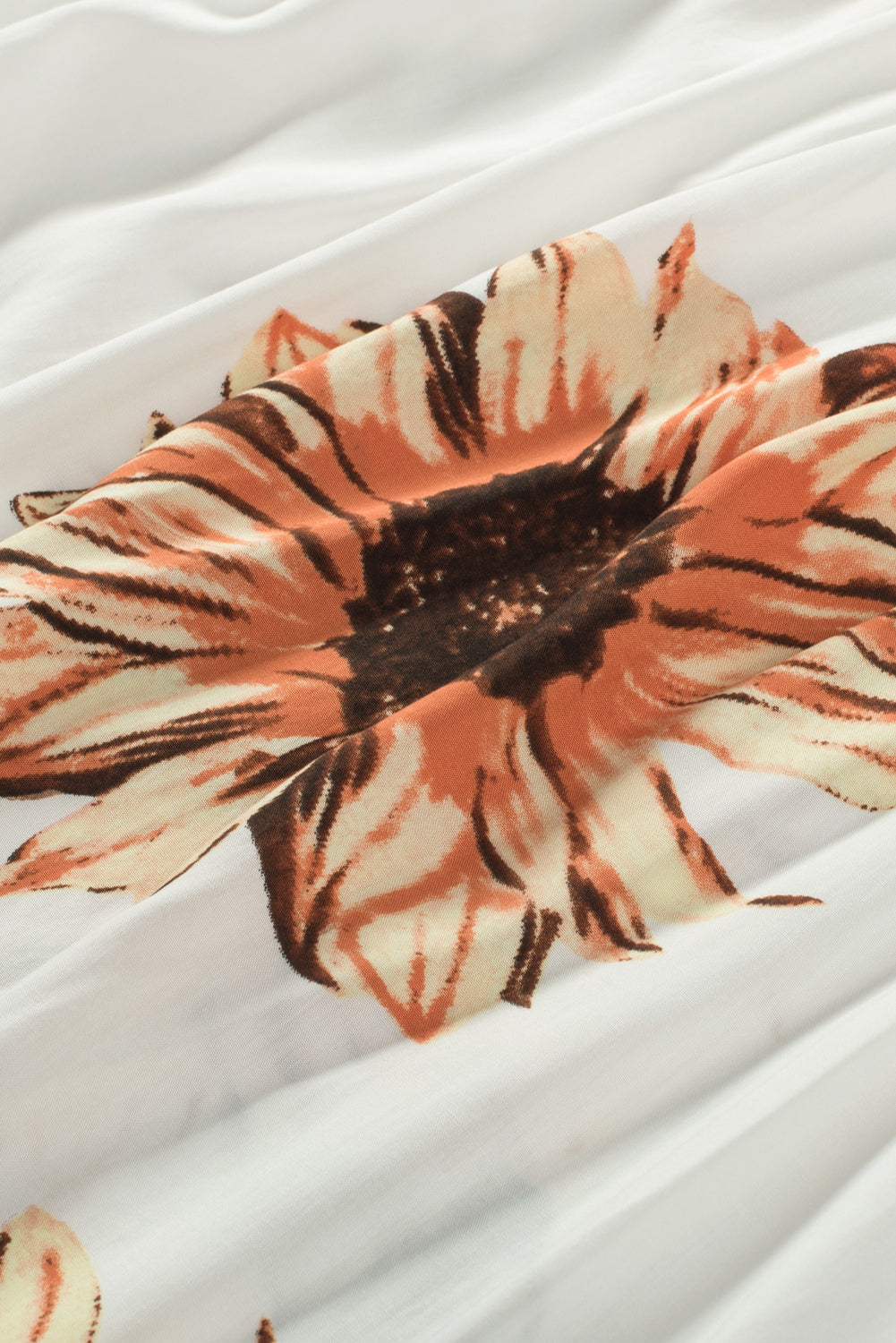 Close-up of a sunflower print on a white fabric, showcasing floral patterns in vibrant hues for a playful blouse.