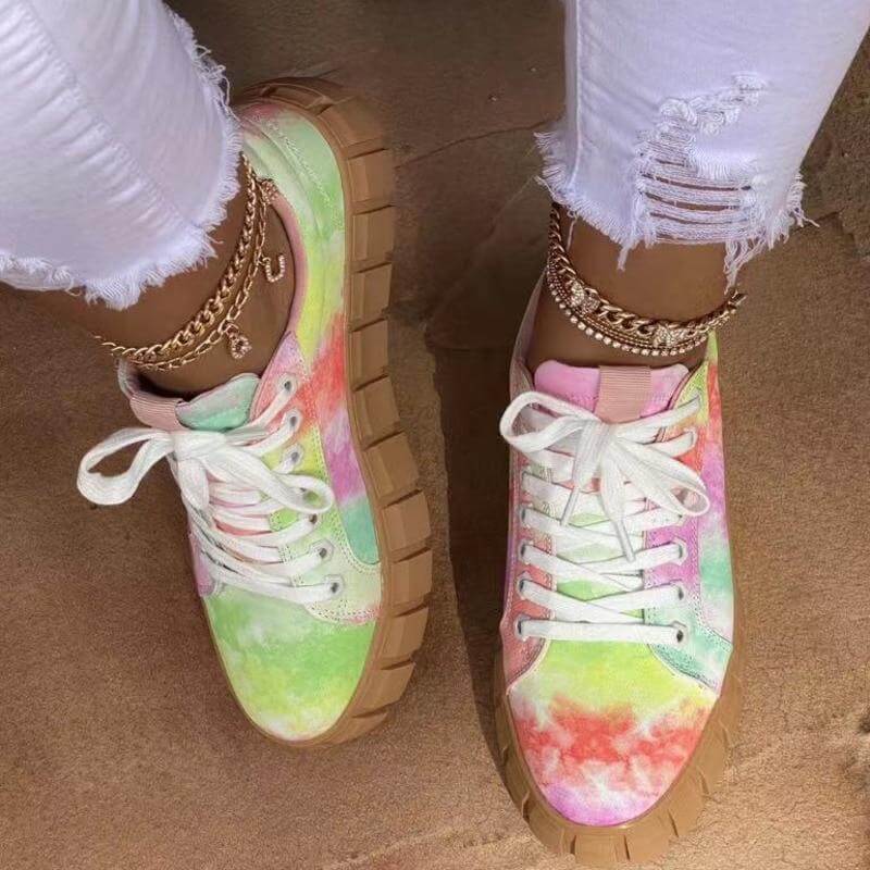 Colorful tie-dye platform sneakers with lace-up detail, styled with distressed white jeans.