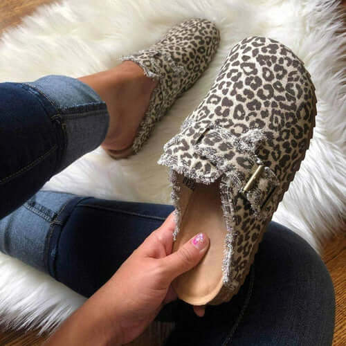 Fashionable leopard print canvas loafers in hand on cozy rug, styled for a chic vintage look.