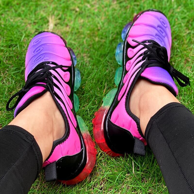 Vibrant pink and purple running sneakers on grass, perfect for summer workouts and fitness training.