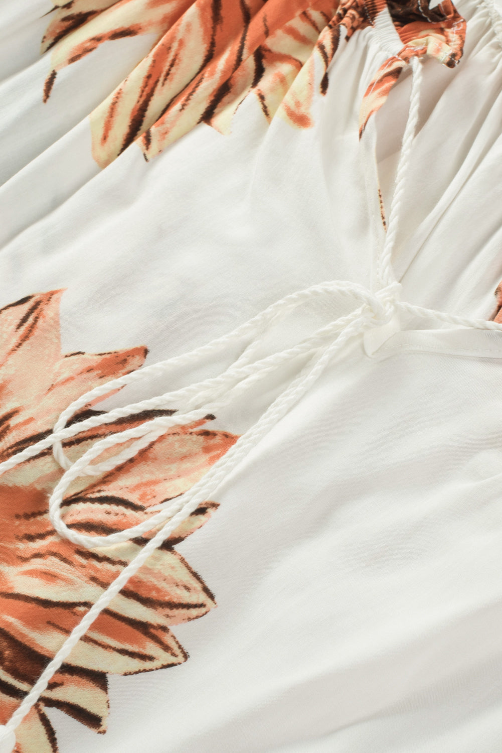 Close-up of floral ruffled tassel tie detail on off shoulder blouse with sunflowers.