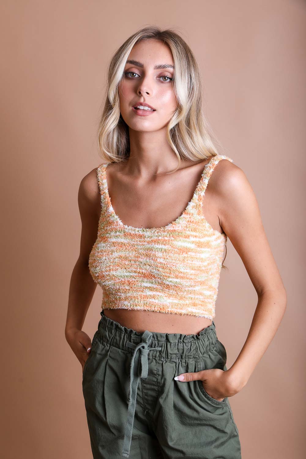 Model wearing a whimsical boucle brami top in orange and cream, paired with casual pants, smiling against a neutral background.