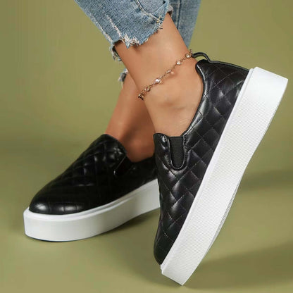 Black quilted slip-on loafers with a white platform, styled with distressed jeans and a trendy ankle bracelet.