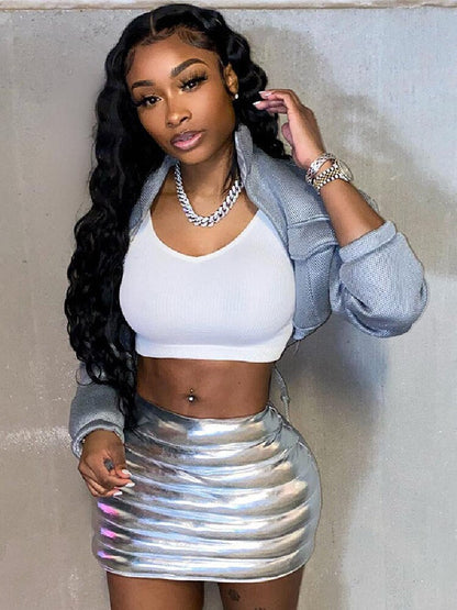 Woman wearing a metallic silver mini puffer skirt and white crop top, showcasing a stylish look with long wavy hair.