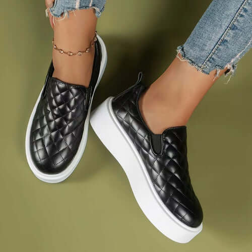 Quilted black slip-on loafers with a lightweight white platform, styled with denim jeans.