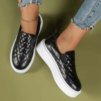 Quilted black slip-on loafers with a lightweight white platform, styled with denim jeans.