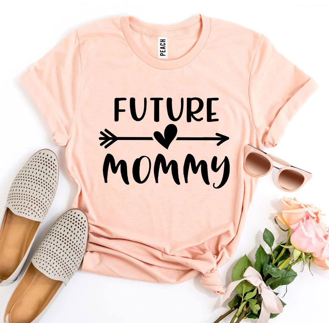 Future Mommy T-shirt in soft peach color with stylish typography, paired with trendy shoes and sunglasses.