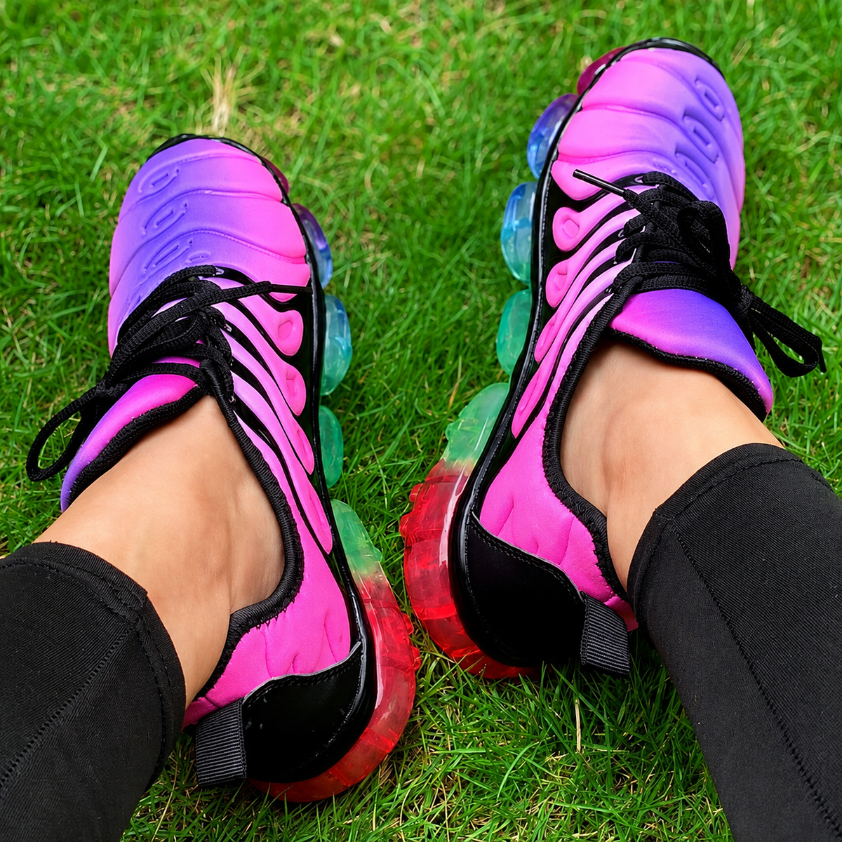 Vibrant pink and purple running sneakers on grass, perfect for summer workouts and fitness training.