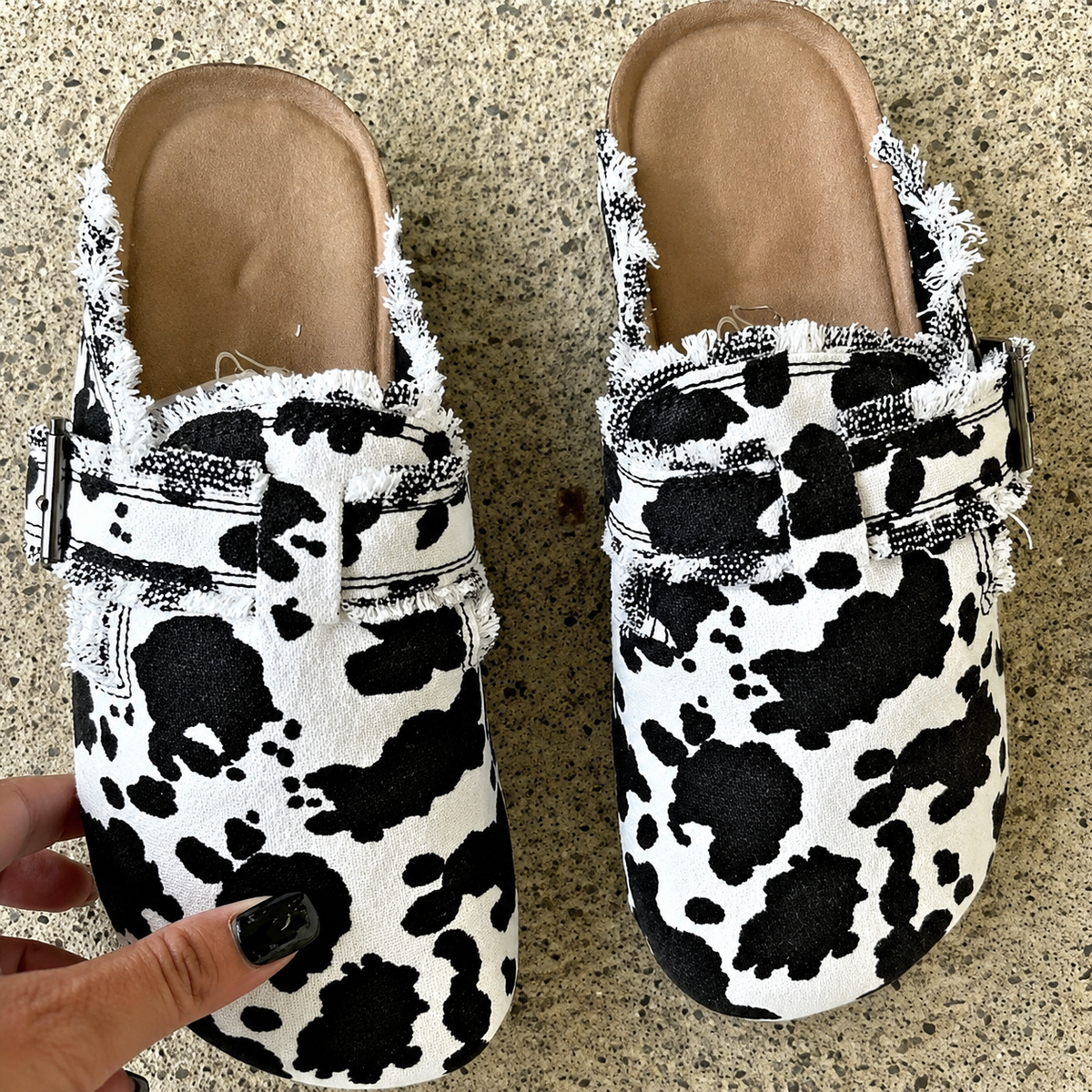 Trendy black and white cow print canvas loafers with a casual open back design.